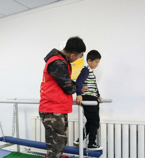图2.志愿者辅助孩子康复训练.jpg